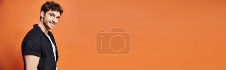 Photo for Joyful young man in casual outfit on orange backdrop looking at camera, fashion concept, banner - Royalty Free Image