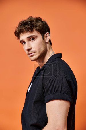 Photo for Handsome young man in casual outfit on orange backdrop looking at camera, fashion concept - Royalty Free Image