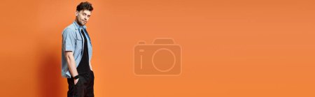 Photo for Cheerful man in casual attire on orange backdrop looking at camera, fashion concept, banner - Royalty Free Image