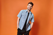 joyous attractive man in casual outfit on orange backdrop looking at camera, fashion concept hoodie #685858900