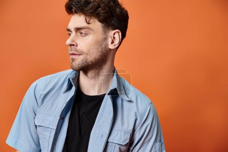 Photo for Good looking man in casual trendy outfit on orange backdrop looking at camera, fashion concept - Royalty Free Image