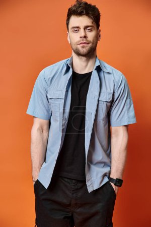 handsome man in casual trendy outfit on orange backdrop looking at camera, fashion concept