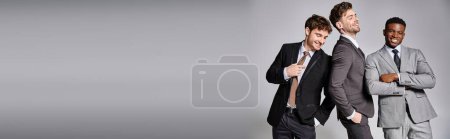 Téléchargez les photos : Modèles masculins multiculturels en tenues décontractées d'affaires posant sur fond gris et souriant joyeusement - en image libre de droit