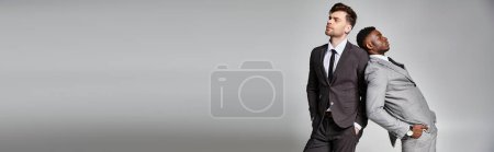 Téléchargez les photos : Deux beaux modèles masculins multiculturels en affaires vêtements intelligents posant sur fond gris, bannière - en image libre de droit