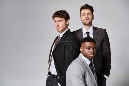 Téléchargez les photos : Beaux jeunes modèles masculins multiculturels en tenue décontractée d'affaires posant sur fond gris - en image libre de droit