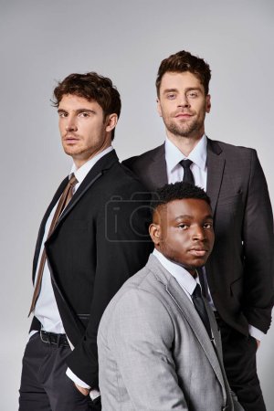 Téléchargez les photos : Attrayants jeunes modèles masculins multiraciaux en tenue décontractée d'affaires posant sur fond gris - en image libre de droit