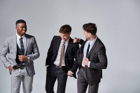 Téléchargez les photos : Attrayant joyeux divers amis en affaires tenues élégantes souriant joyeusement sur fond gris - en image libre de droit