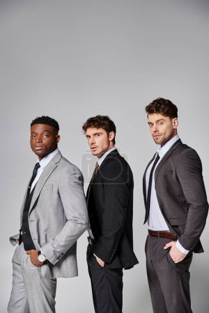 Téléchargez les photos : Beaux modèles masculins multiculturels élégants en tenue décontractée d'affaires posant sur fond gris - en image libre de droit