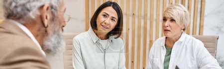 Photo for Middle aged multicultural lesbian couple sitting next to realtor in real estate office, banner - Royalty Free Image