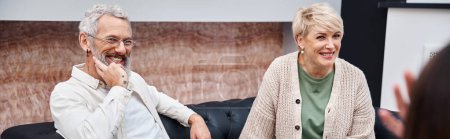 Photo for Happy middle aged couple sitting on couch and looking at psychologist during consultation, banner - Royalty Free Image
