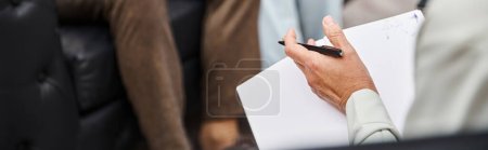 Photo for Focus on psychologist  holding pen and blank notebook near married couple during appointment, banner - Royalty Free Image