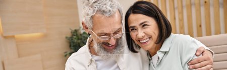 happy bearded man hugging multiracial wife while purchasing new house in real estate office, banner
