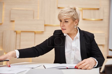 blonde middle aged realtor with short hair working in real estate office, busy working day