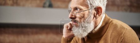 bearded middle aged psychologist in glasses looking away and listening during session, banner