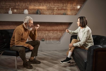 bearded middle aged psychologist in glasses talking with female client during therapy session