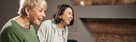 cheerful  middle aged lesbian couple smiling while sitting on couch during therapy session, banner