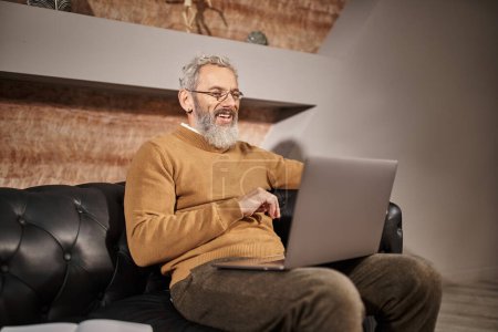 joyeuse psychologue d'âge moyen avec barbe parler lors de la consultation en ligne avec le client sur ordinateur portable