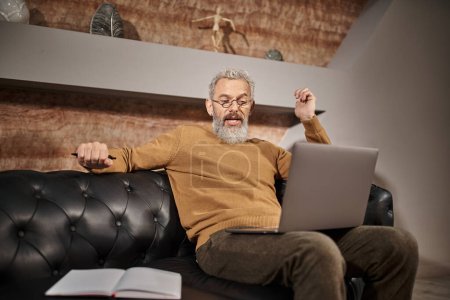middle aged psychologist with beard talking to client during online consultation on laptop