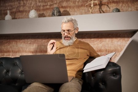 middle aged psychologist with beard talking to client during virtual consultation on laptop