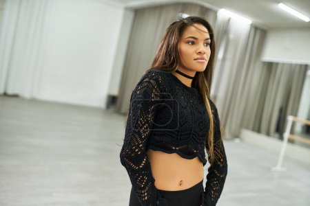 long-haired african american female dancer in crop knitted sweater rehearsing in dancing hall