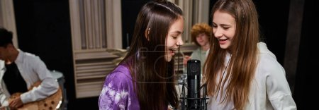 pretty cheerful teenage girls singing while boys playing drums and guitar, musical group, banner