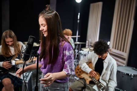 lustige süße Teenager in alltäglicher lebendiger Kleidung, die Instrumente spielen und aktiv im Studio singen