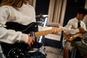 cropped view of talented teenage girl playing guitar next to her friend in studio, musical group Stickers #687122390