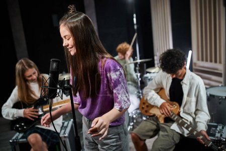 konzentrieren sich auf fröhliche Teenager-Mädchen singen, während ihr Freund verschiedene Instrumente spielt, musikalische Gruppe