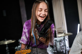 joyous adorable teenage girl in vibrant attire singing actively into microphone while in studio Poster #687122610