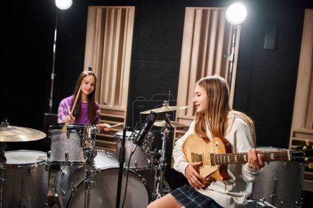 Foto de Dos chicas adolescentes bastante talentosas en trajes casuales tocando la guitarra y la batería, grupo musical - Imagen libre de derechos