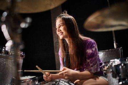 Foto de Alegre adorable adolescente en casual traje jugando batería felizmente mientras en música studio - Imagen libre de derechos