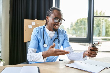 Photo for Jolly young african american doctor with glasses consulting someone by mobile phone, telemedicine - Royalty Free Image