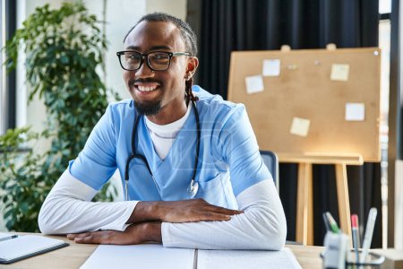 handsome cheerful african american doctor with glasses looking at camera during online consultation
