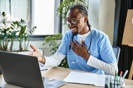 Téléchargez les photos : Médecin afro-américain joyeux avec des lunettes consulter quelqu'un par téléphone et gesticuler activement - en image libre de droit