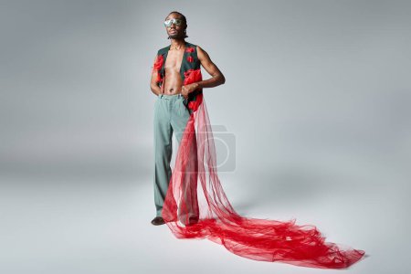 junger afrikanisch-amerikanischer Mann mit Sonnenbrille in lebendiger Kleidung blickt in die Kamera, Modekonzept