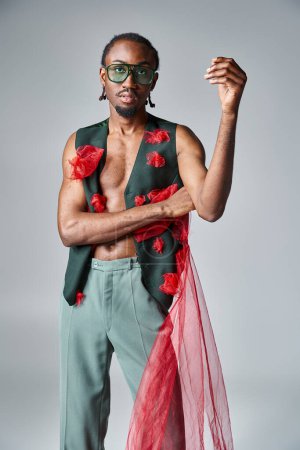 schöner afrikanisch-amerikanischer Mann mit Sonnenbrille in lebendiger Kleidung, der in die Kamera schaut, Modekonzept