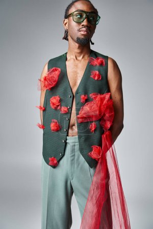handsome african american man in trendy vest with red tulle fabric looking away, fashion concept