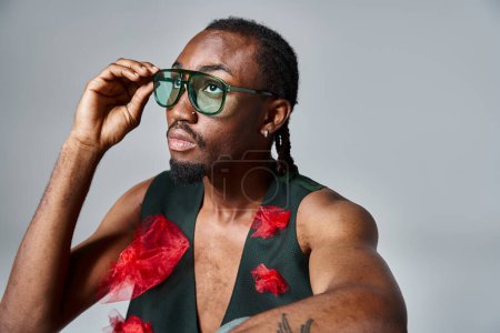 Téléchargez les photos : Élégant homme afro-américain avec du tissu de tulle rouge sur son gilet détournant les yeux, concept de mode - en image libre de droit