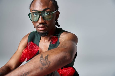 Téléchargez les photos : Portrait de bel homme afro-américain en vêtements vibrants avec des lunettes de soleil, concept de mode - en image libre de droit