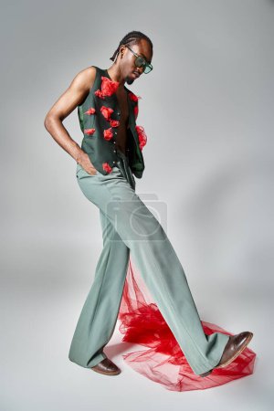 Téléchargez les photos : Élégant modèle masculin afro-américain avec tissu en tulle rouge posant en mouvement et détournant les yeux - en image libre de droit