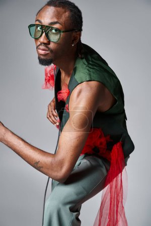 schöner afrikanisch-amerikanischer Mann mit trendiger Sonnenbrille posiert in Bewegung und blickt in die Kamera
