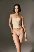 pretty asian woman in fishnet tights and beige corset posing on grey background, female grace Tank Top #688147150