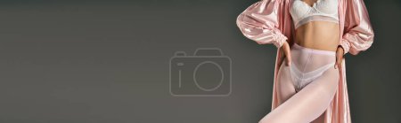 Téléchargez les photos : Femme recadrée en robe rose et collants blancs posant avec les mains sur les hanches sur fond gris, bannière - en image libre de droit