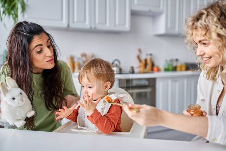 fröhlich gefesseltes lesbisches Paar beim leckeren Frühstück mit ihrem kleinen Mädchen, Familienkonzept