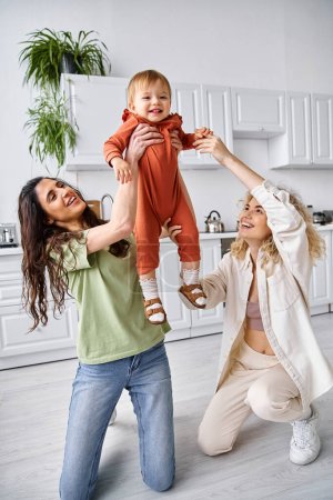 charming happy lgbt couple playing actively with their cute toddler daughter, modern parenting