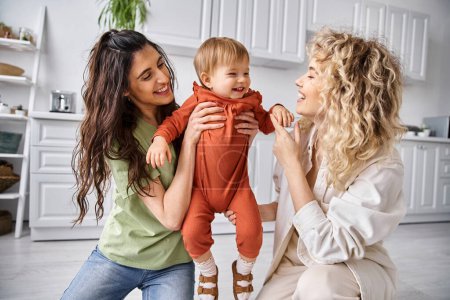 attractive happy lgbt couple playing actively with their pretty toddler daughter, modern parenting