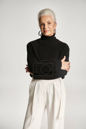 Geschäftsporträt einer Geschäftsfrau mittleren Alters in schicker Freizeitkleidung, die vor grauem Hintergrund posiert
