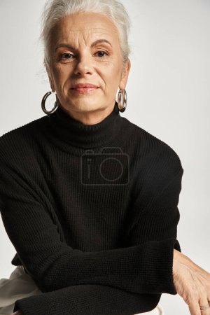 Geschäftsporträt einer Geschäftsfrau mittleren Alters in schicker Freizeitkleidung, die in grau in die Kamera blickt