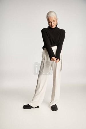 full length of happy middle aged business woman in elegant smart casual attire posing on grey