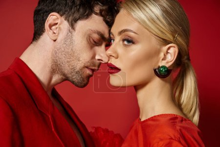 handsome man posing with beautiful blonde woman with red lips on vibrant background, fashion